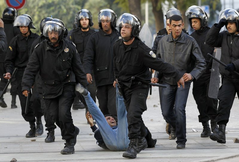 In this Friday, Jan. 14, 2011, file photo, riot police officers detain a protestor during clashes in Tunis.