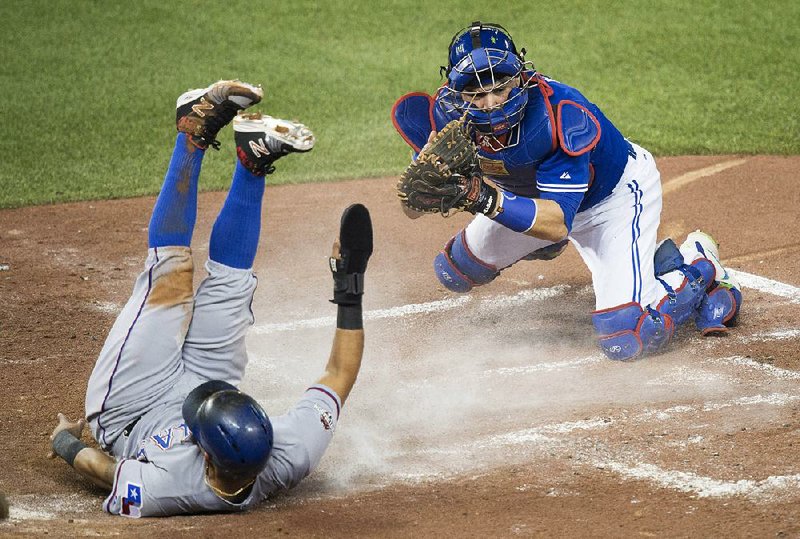 Texas Rangers second baseman Rougned Odor (left) ends up on his back after scoring on a sacrifice fly in the second inning of the Rangers’ 6-4 victory over the Toronto Blue Jays on Friday in Game 2 of the American League division series. The Rangers have a 2-0 lead in the series.