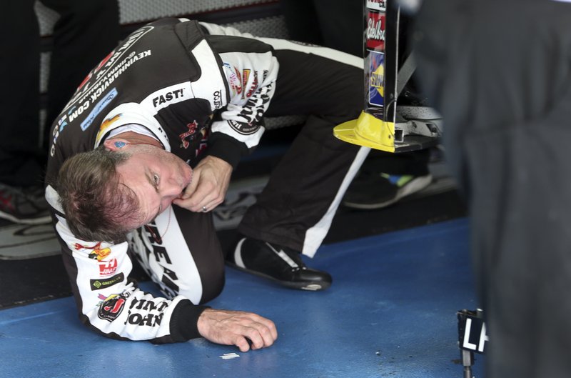 Kevin Harvick looks under his car during during practice for Saturday's NASCAR Sprint Cup series auto race at Charlotte Motor Speedway in Concord, N.C., Friday, Oct. 9, 2015.