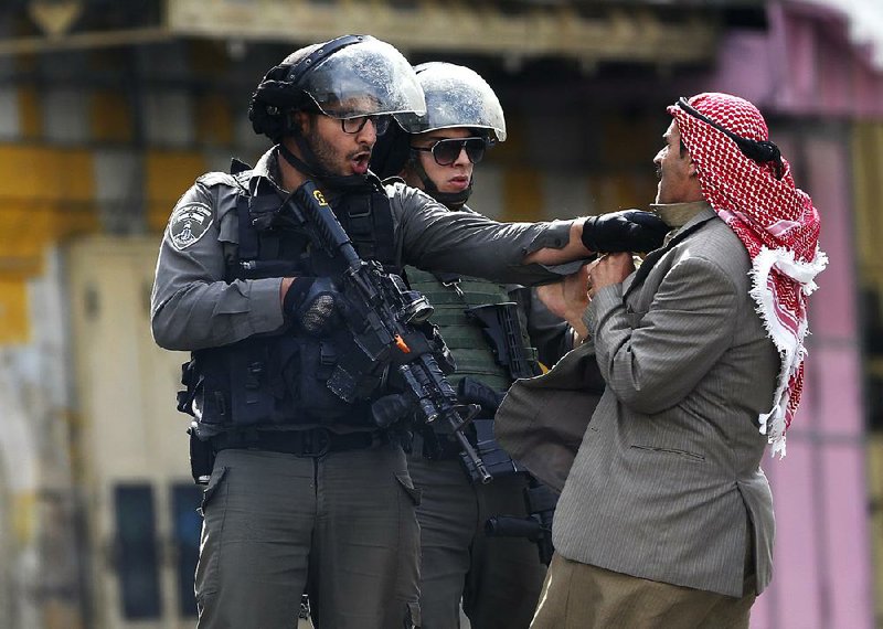 Israeli police officers grapple with a Palestinian man Saturday in the West Bank city of Hebron. Unrest continued in the West Bank, Gaza and Jerusalem, and two police officers were stabbed Saturday in Jerusalem’s Old City. The attacker was shot and killed by police, and an officer was wounded by gunfire.