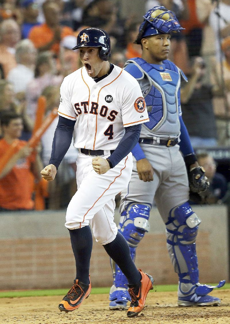 Houston’s George Springer (4) reacts after scoring in front of Kansas City catcher Salvador Perez during the Astros’ 4-2 victory in Game 3 of their American League division series Sunday.