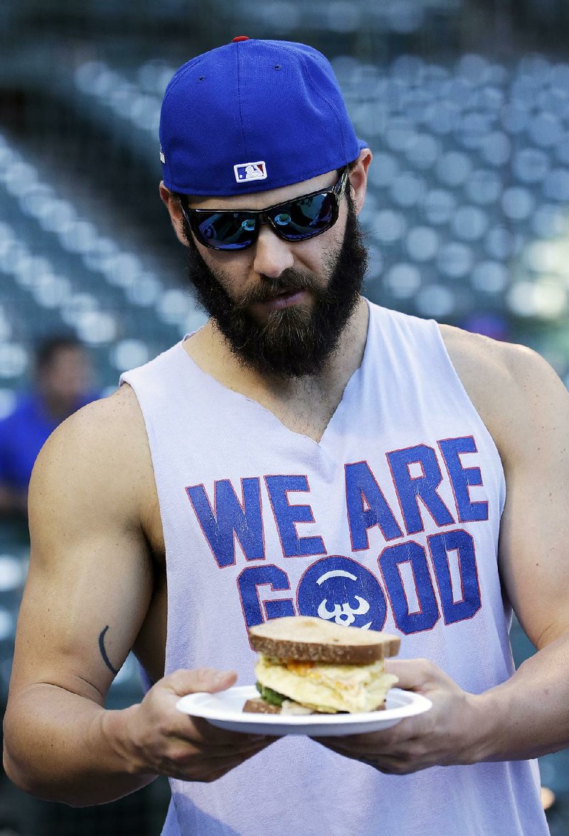 Chicago Cubs pitcher Jake Arrieta checks his sandwich before an NLDS baseball practice on Sunday, Oct. 11, 2015 in Chicago. The Cubs are to face the St. Louis Cardinals in Game 3 of the National League Division Series on Monday. 