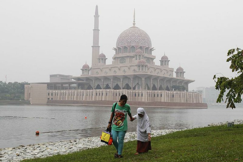 A woman and child stroll past the Putra Mosque in Putrajaya, Malaysia, on a smoggy day in late September. 