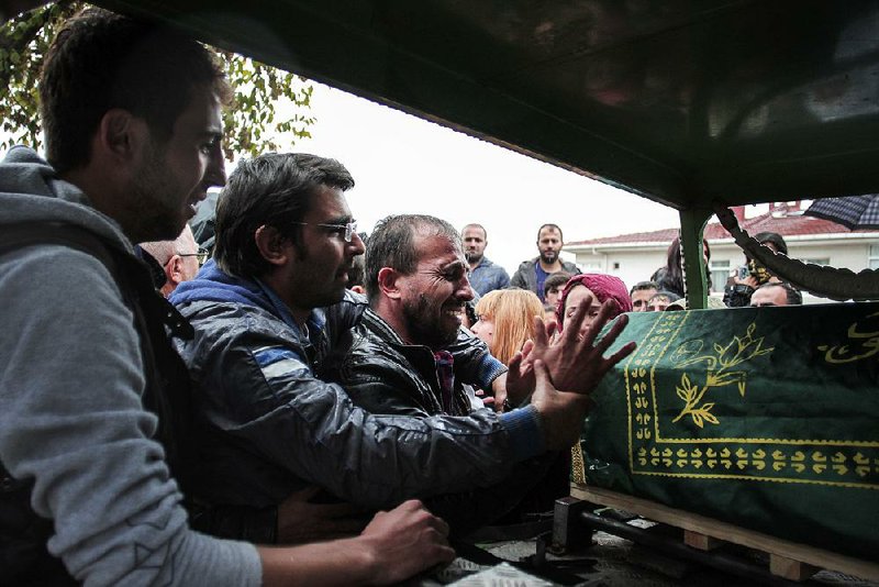 The brother of Sarigul Tuylu, 35, a mother of two who was killed in Saturday’s bombing attacks in Ankara, Turkey, cries over her coffin during her funeral in Istanbul on Sunday.