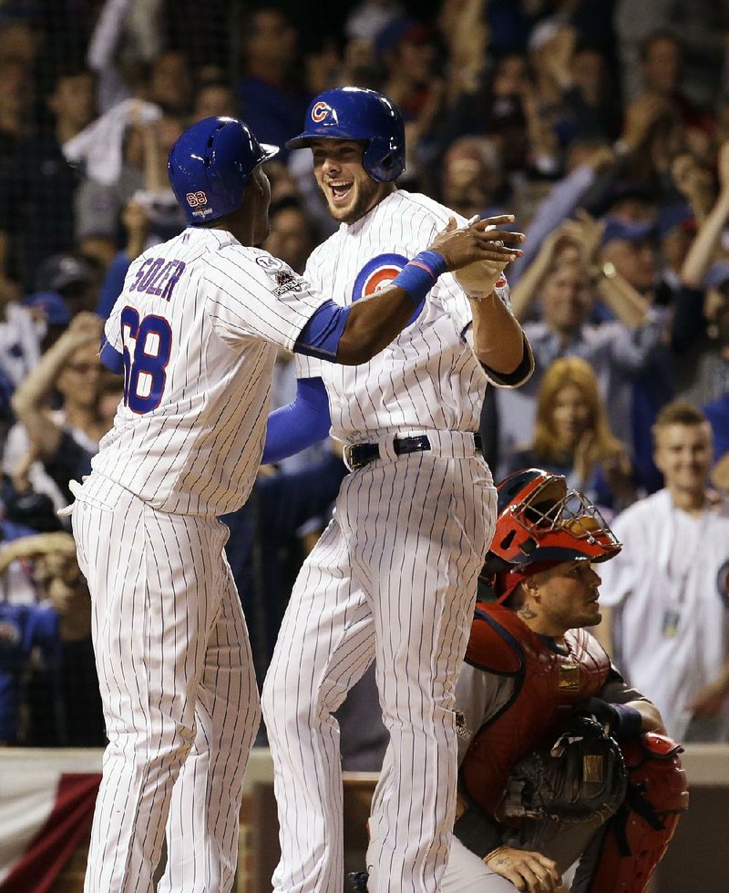 Chicago third baseman Kris Bryant (right) is met at home plate by Jorge Solor after Bryant hit a two-run home run in the fifth inning of Monday’s game against St. Louis. Soler added a home run in the sixth inning to help the Cubs beat the Cardinals 8-6 to take a 2-1 lead in their National League division series.
