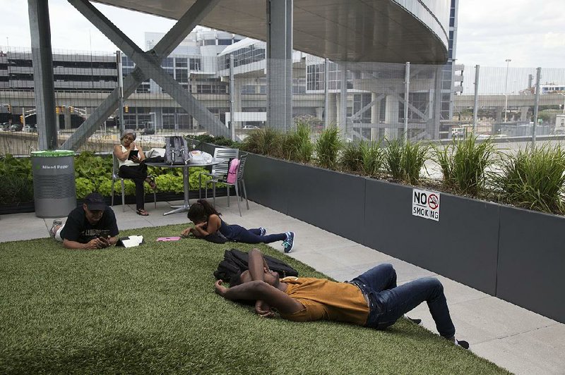 Travelers wait in August at JetBlue Airways Corp.’s outdoor space at John F. Kennedy International Airport in New York. The airport’s TWA Flight Center is to be converted to a hotel complex, with JetBlue as a minority partner.