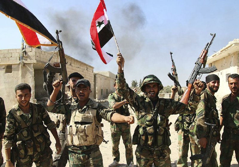 Syrian soldiers waving fl ags celebrate Sunday the capture of Achan in Hama province. Russian jets intensified their airstrikes Monday as Syrian government and allied troops pushed insurgents from villages and expanded their control of the area, activists and a military statement said.