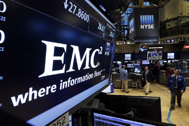 Traders work Monday near the post that handles EMC Corp. on the fl oor of the New York Stock Exchange.