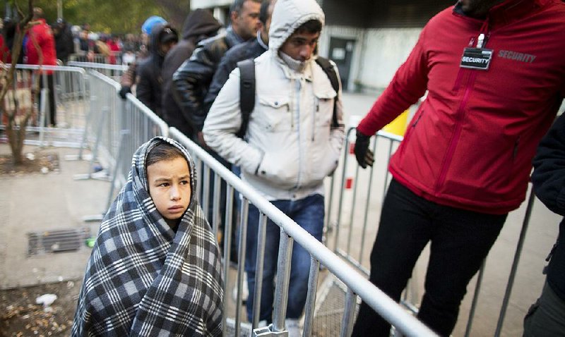 A child uses a blanket as protection from below-freezing temperatures Monday while migrants wait to register at the State Office of Health and Welfare in Berlin.
