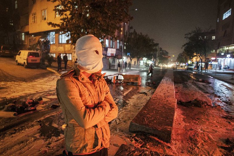 A masked leftist militant stands at a barricade Monday in Istanbul’s Gazi district during clashes with Turkish security forces at a protest held in response to Saturday’s Ankara bombing attacks.

