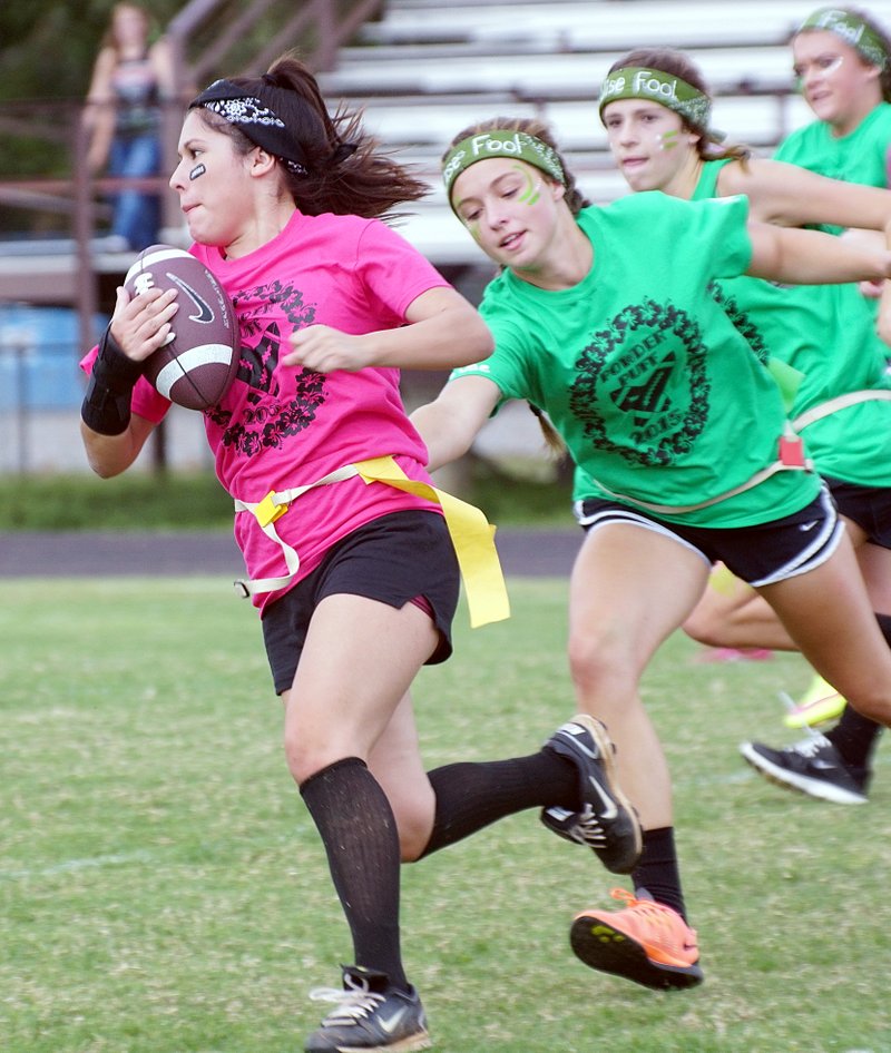 Lali Estrada carries the ball for the juniors but is pursued by sophomore Kya DeZurik during powder puff football at Gentry High School on Sept. 30.