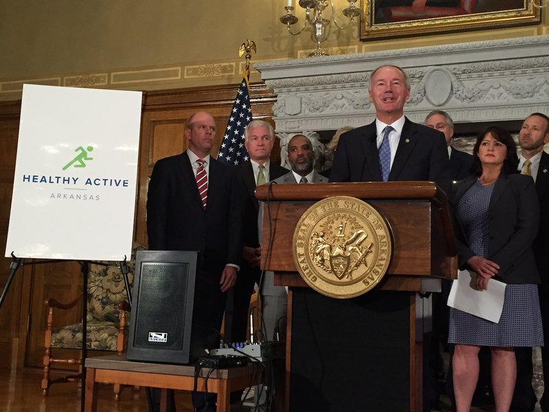 Gov Asa Hutchinson, surrounded by leaders behind a 10-year plan to curb the state's obesity rate, announces the Healthy Active Arkansas initiative during a news conference at the state Capitol on Wednesday, Oct. 14, 2015.