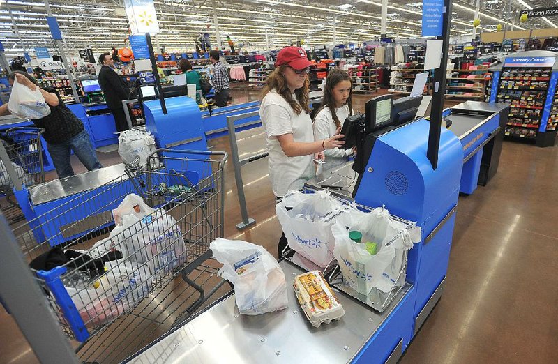 Sydney Walsh, left, and Channing Daniels use the new self-checkout lanes recently at a Wal-Mart Supercenter in Rogers. Once built by the hundreds annually, supercenters will grow between 50 and 60 in the retailer’s next fiscal year as it grapples with ways to improve earnings.
