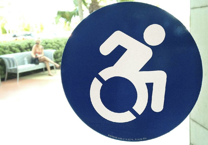 A modernized handicapped sign is affixed to a door at the The Mall at Millenia in Orlando, Fla. Advocates want to replace the familiar image of a stick figure in a wheelchair with this action-oriented logo to emphasize ability, not disability.
