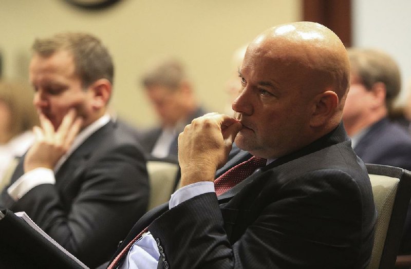 Richard Bateson (left) of Camelot Global Services and lottery Director Bishop Woosley listen Friday as the Arkansas Legislative Council discusses a contract with the company to develop a business plan for the lottery.
