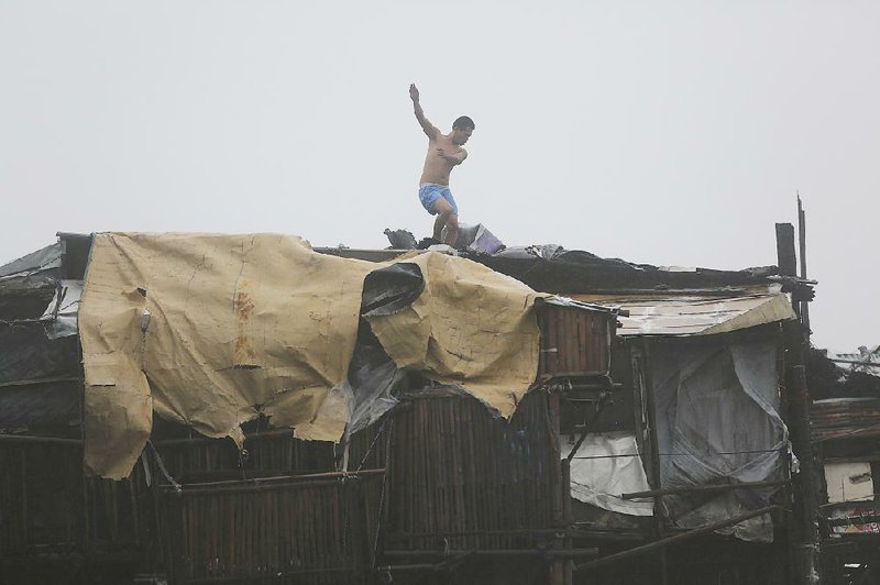 A man is thrown off balance by strong winds caused by Typhoon Koppu as he tries to reinforce the roof of his house in the coastal town of Navotas, north of Manila, Philippines, on Sunday.
