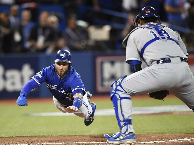 Toronto’s Kevin Pillar (left) dives for home plate as Kansas City catcher Salvador Perez awaits the throw during the second inning of Game 3 in the American League Championship Series on Monday. Pillar scored on the play to help the Blue Jays cut their series deficit to 2-1 with an 11-8 victory in front of a sold-out crowd of 49,751 at the Rogers Centre in Toronto.