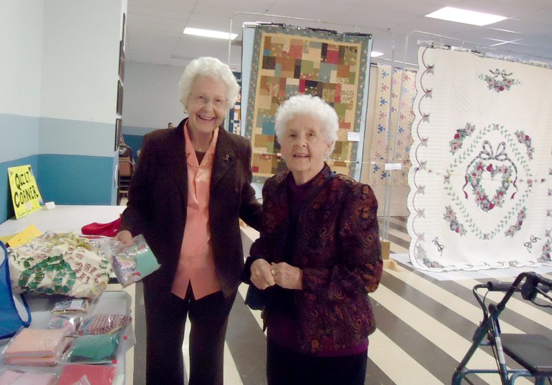 Photo by Cinda Paulson Lou Romine, left, of Gravette, visited with Maxine Paulson, of Noel, Mo., at Saturday&#8217;s quilt show and looked over some of the fabric squares offered for sale. Lou is instructor of the PieceMaker Quilters group and Maxine is the oldest member of the group, having just celebrated her 91st birthday last week.