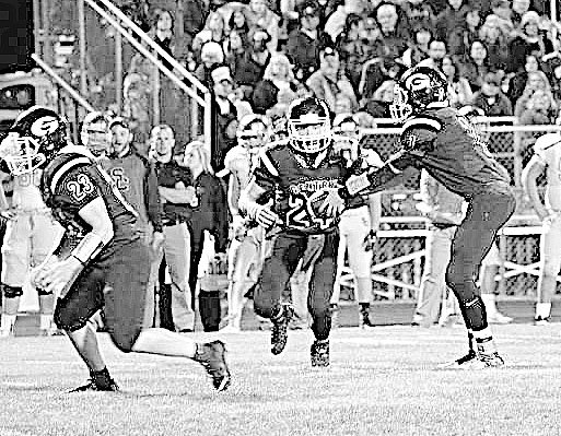 Photo by Mike Eckels Jon Faulkenberry hands off the ball to Cole Cripps behind the blocking of Tanner Christie during play against the Saints from Shiloh Christian on Friday in Gentry.