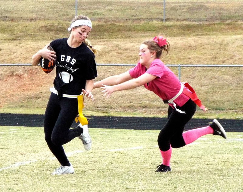 Photo by Randy Moll Kendall Yarbrough, of the sophomore team, reaches for the flags of Sam Roth, senior team, but misses during powder puff play on Saturday in Gravette. The seniors won, 28-7.