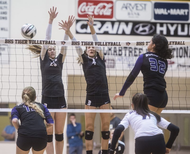 Haley Warner (32) of Fayetteville spikes a shot past Grace Joyce (23) and Sadie Pate (4) of Bentonville Tuesday, Oct. 20, 2015 at Tiger Arena in Bentonville. The Lady Bulldogs won 3-1 going undefeated in 7A conference play.