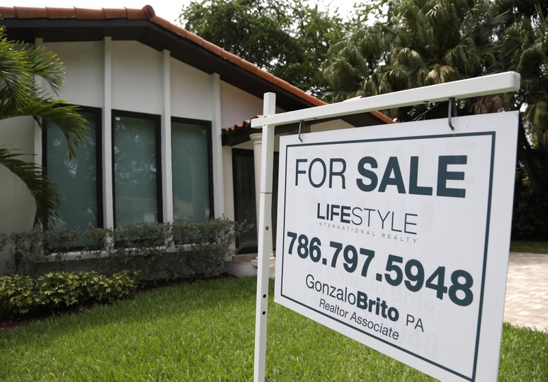 In a Saturday, Aug. 15, 2015, file photo, a realty sign hangs in front of a home for sale in Miami. The National Association of Realtors reports on sales of existing homes in September on Thursday, Oct. 22, 2015.