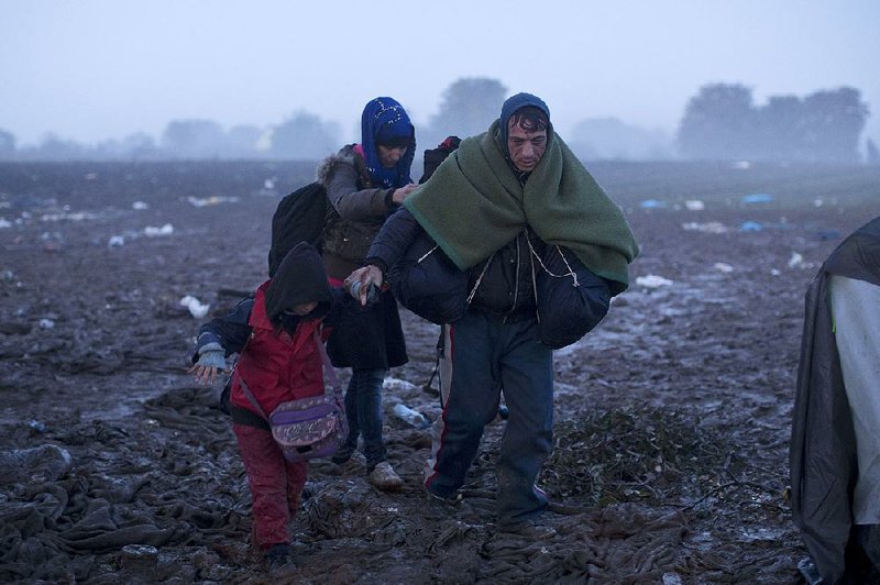 Members of a migrant family walk through a muddy field Friday in northwestern Serbia near the border with Croatia after they and thousands of others spent the rainy night in near-freezing conditions.