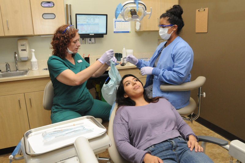 Dr. Shannon G. Wright (left) and assistant Danelzy Castillo demonstrate how they did an examination earlier in the day Oct. 20 for Marcela Rodriguez of Centerton (center).