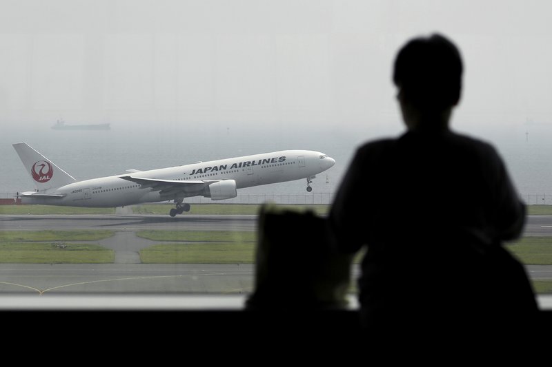 A visitor looks out from a window as a Boeing Co. 777 aircraft operated by Japan Airlines Co. takes off at Haneda Airport in Tokyo, Japan in April.
