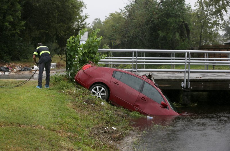 Eric Plumber, a tow truck driver, works to get a car out of a bayou Sunday in Houston.