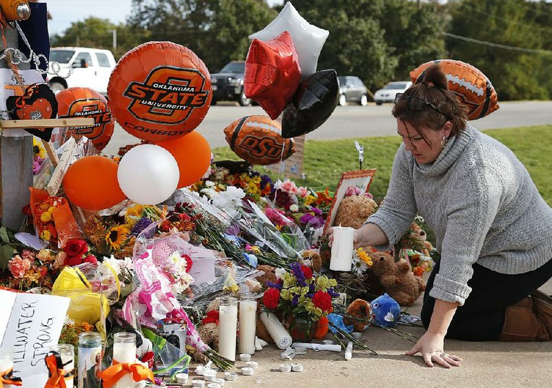 Stefanie Alexander, who witnessed the Saturday homecoming parade crash in Stillwater, Okla., places a candle at a makeshift memorial Monday.