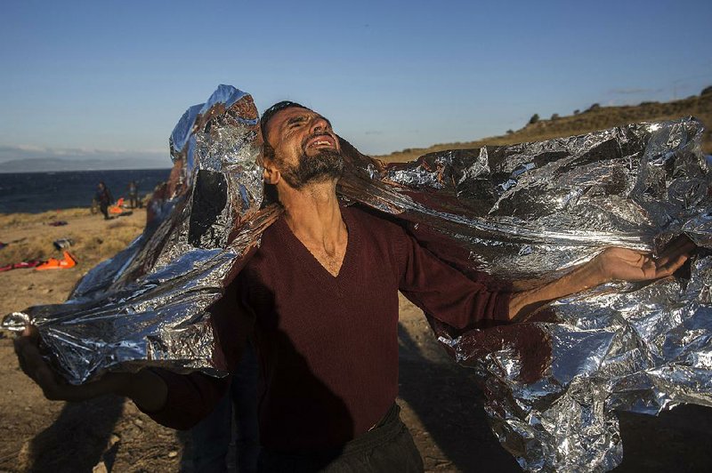 A man wearing a thermal blanket reacts Wednesday after arriving in bad weather from Turkey on the Greek island of Lesbos in a dinghy. 