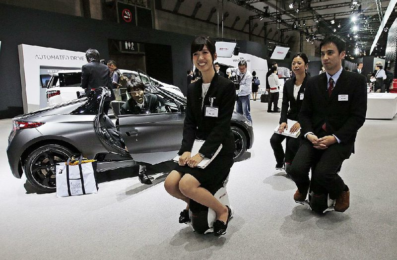 Honda Motor Co. employees ride Honda UNI-CUB devices around the automaker’s booth Wednesday during a preview of the Tokyo Motor Show. 