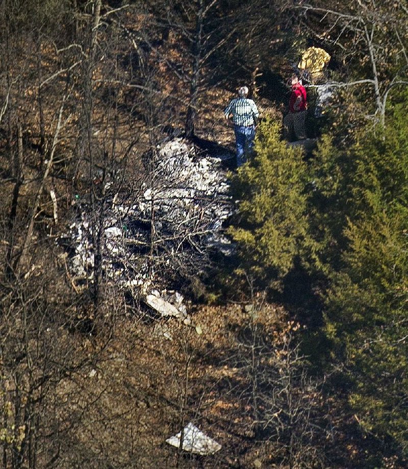 Investigators examine the wreckage of a Beechcraft Bonanza plane that crashed Thursday on Crow Mountain, east of the Russellville airport. More photos are available at arkansonline.com/galleries. 