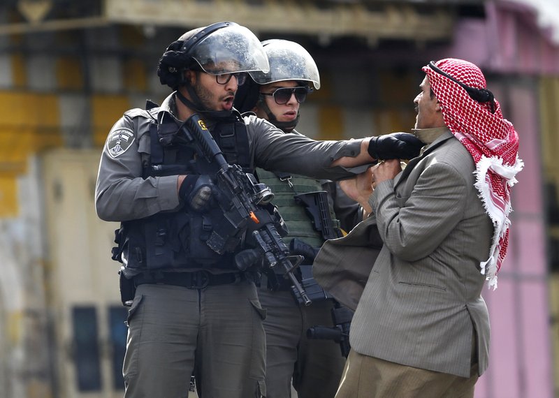 A Palestinian is pushed by an Israeli policeman Oct. 10 during clashes in Hebron, West Bank.