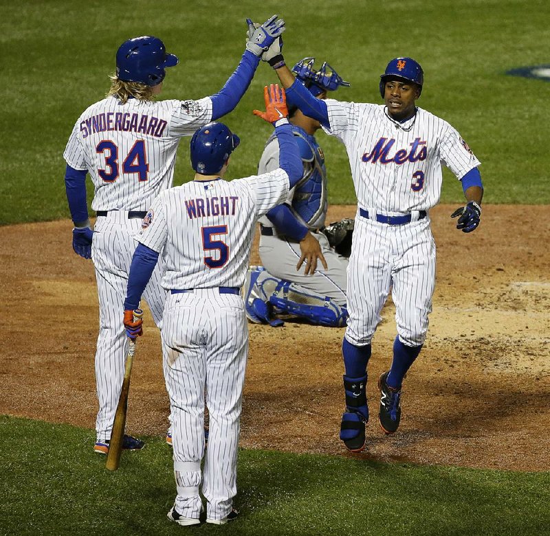 New York’s Curtis Granderson (3) is met at home plate by teammates Noah Syndergaard (34) and David Wright after hitting a home run during the third inning of Game 3 of the World Series on Friday. The Mets cut the series deficit to 2-1 with a 9-3 victory. For more on the Web, visit arkansasonline.com/15serieslineups.
