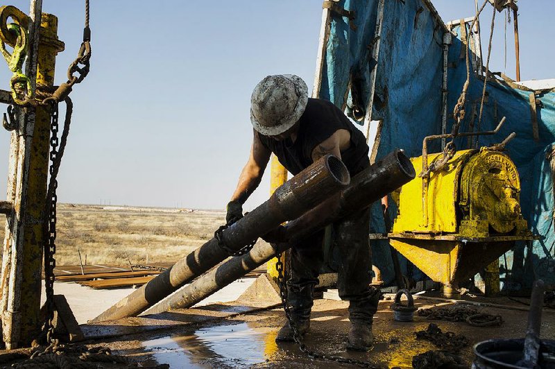 A roughneck pulls a drill part onto the floor of a rig in the Permian basin outside Midland, Texas, in a file photo. Oil-field services discounts and more efficient drilling have helped the oil industry cope with the drop in crude prices.
