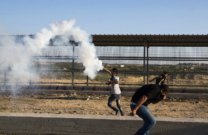 Palestinian protesters dodge tear-gas fumes during clashes Friday with Israeli soldiers securing the Erez border crossing into the Gaza Strip.