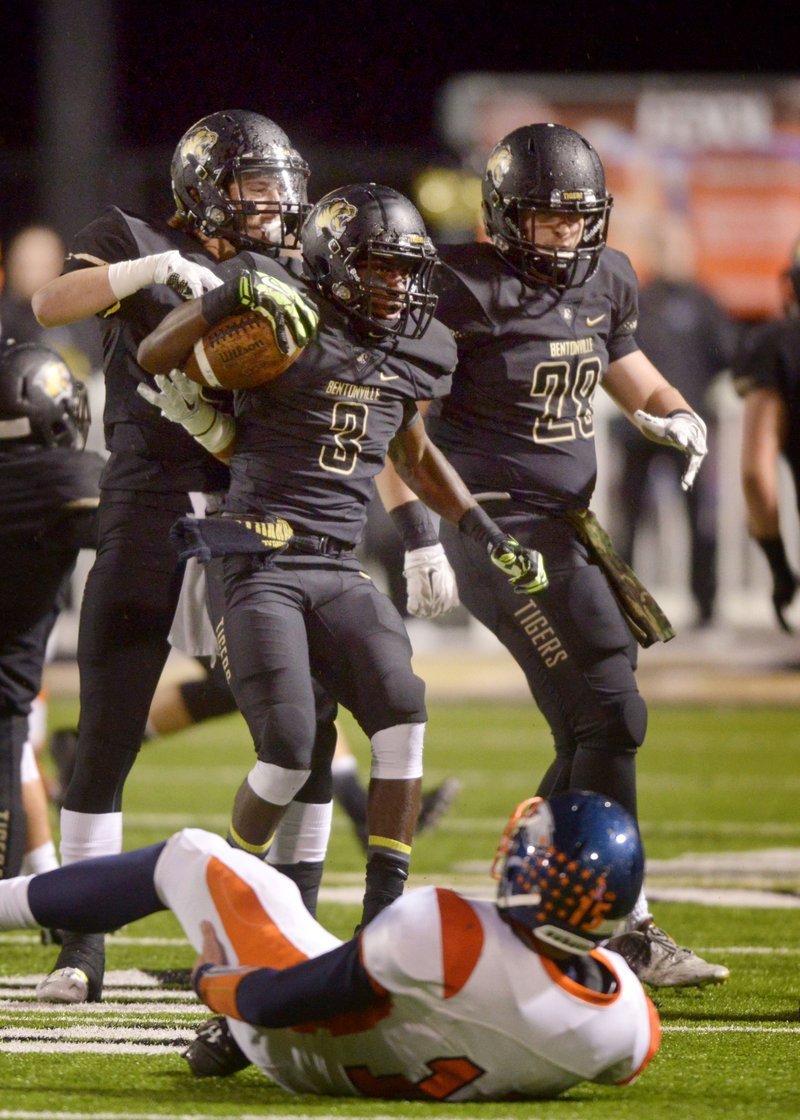 Logan Darby, Bentonville defensive back, and Brandon Atchison (28), Bentonville linebacker, celebrate with Kary Collier (3), Bentonville defensive back, after Collier intercepted a pass intended for Rogers Heritage wide receiver Dylan Qualls (15) on Friday Oct. 30, 2015 in the first quarter of the game in Bentonville&#8217;s Tiger Stadium.