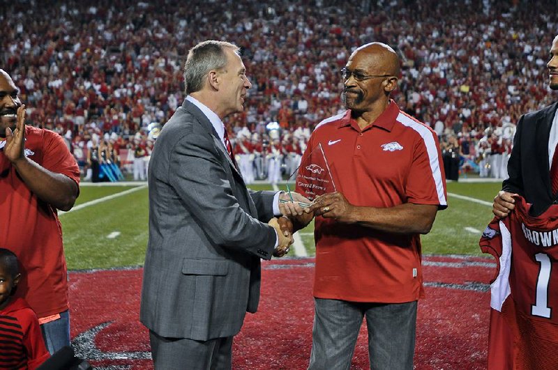 Arkansas Athletic Director Jeff Long (left) presents Little Rock attorney Darrell Brown with a trophy naming him a “Razorback Trailblazer” during halftime of the Arkansas-Auburn game in 2011. Brown, 67, the first black football player at Arkansas, died Saturday.