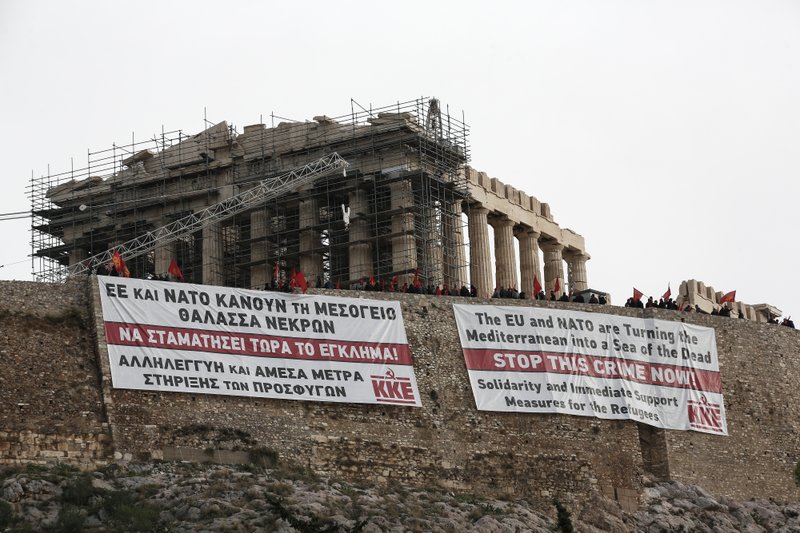 Supporters of the communist-affiliated union PAME stand atop the Acropolis hill after hanging banners, in English and Greek, demanding help for refugees, in front of the temple of the Parthenon in Athens, Saturday, Oct. 31, 2015. At least 27 people, more than half of them children, died in waters off Greece Friday trying to fulfill their dream of a better life in Europe. The tragedy came two days after a boat crammed with 300 people sank off Lesbos in one of the worst accidents of its kind, leaving 29 dead.