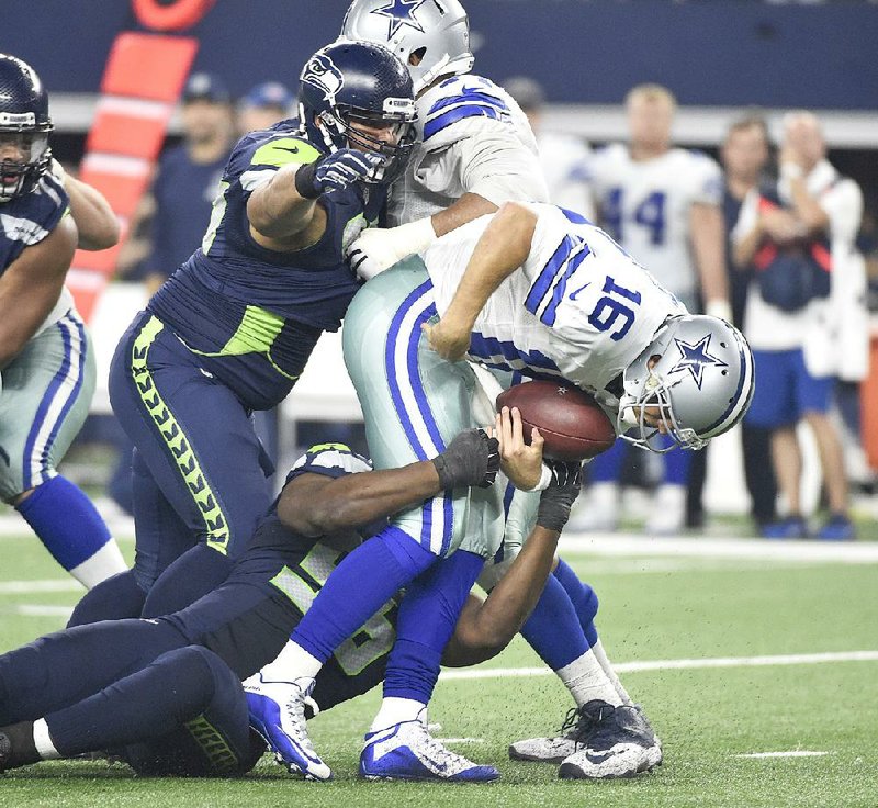Seattle defenders Cliff Avril (bottom) and Jordan Hill (left) sack Dallas quarterback Matt Cassel in the second half of Sunday’s game. The Seahawks got a 24-yard field goal from Steven Hauschka with 1:06 left in the game to beat the Cowboys 13-12.