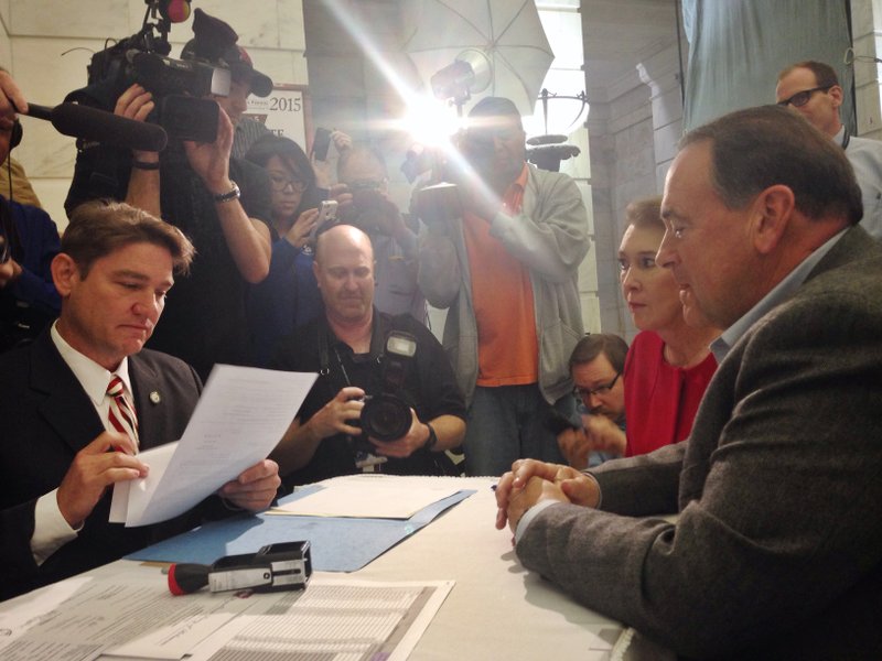 Arkansas Secretary of State Mark Martin reviews paperwork filed by Republican presidential candidate and former Arkansas Gov. Mike Huckabee at the state Capitol on Monday, Nov. 2, 2015.