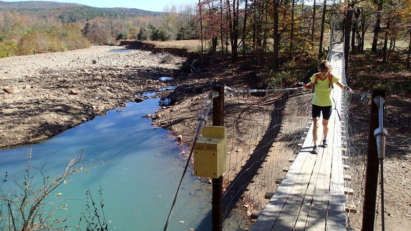 Karen Mowry crosses the Mulberry River Monday on a swinging bridge at Catalpa along Arkansas 215.