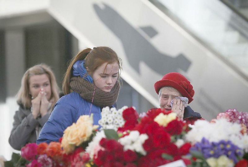 People react at an entrance of Pulkovo airport outside St. Petersburg, Russia, on Tuesday during a day of national mourning for the victims of Saturday’s plane crash. Thousands of people flocked to St. Petersburg’s airport, laying flowers and other items next to the pictures of the victims of the crash of the passenger jet in Egypt. 