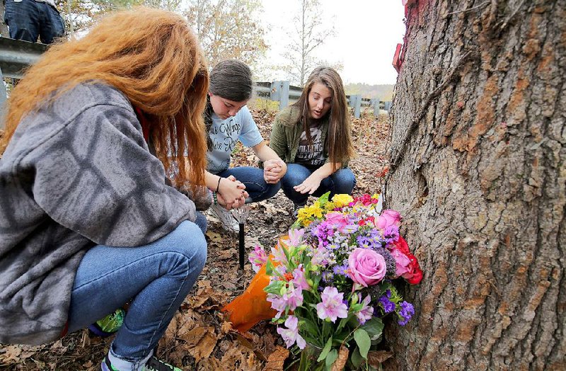 Cabot High School student Riley Eakin (right) leads classmates Kaylin Braughton (left) and Megan Viele in prayer Wednesday at the Gravel Hill Road site in White County where four Cabot High School students and former students were killed in a vehicle accident Halloween night.