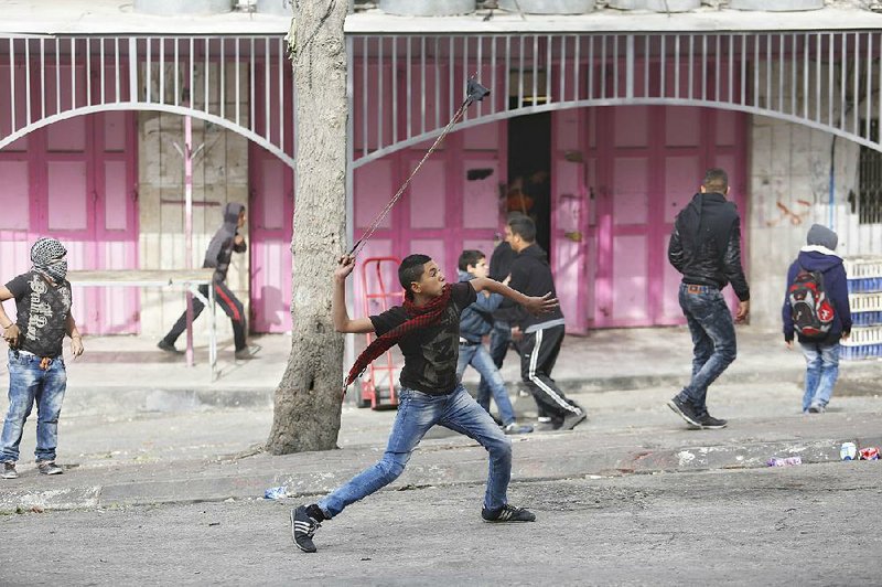 A Palestinian youth fires stones from his slingshot at Israeli troops Wednesday in the West Bank city of Hebron. 
