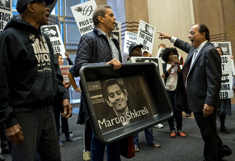 In this Thursday, Oct. 1, 2015, file photo, carrying an image of Turing Pharmaceuticals CEO Martin Shkreli in a makeshift cat litter pan, AIDS activists and others are asked to leave the lobby of 1177 6th Ave. in New York, during a protest highlighting pharmaceutical drug pricing.