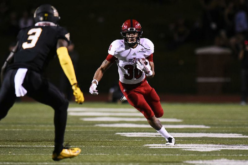 Arkansas State running back Johnston White (30) looks for running room as Appalachian State defensive back Alex Gray closes in during Thursday’s game. The Red Wolves took over sole possession of first place in the Sun Belt Conference with a 40-27 victory.Photo courtesy of Arkansas State
