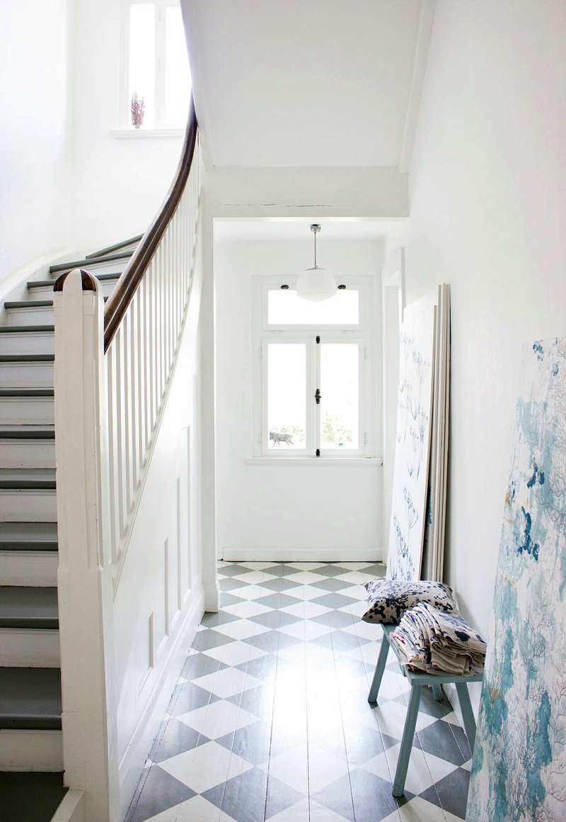 A white and gray checkerboard pattern painted on this hardwood floor brings the elegance of a tile floor to this otherwise casual, unpretentious hallway.